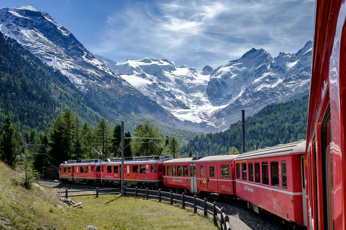 A red Bernina Express train rounds the Montebello curve, with the Morteratsch Glacier and snowy peaks behind.